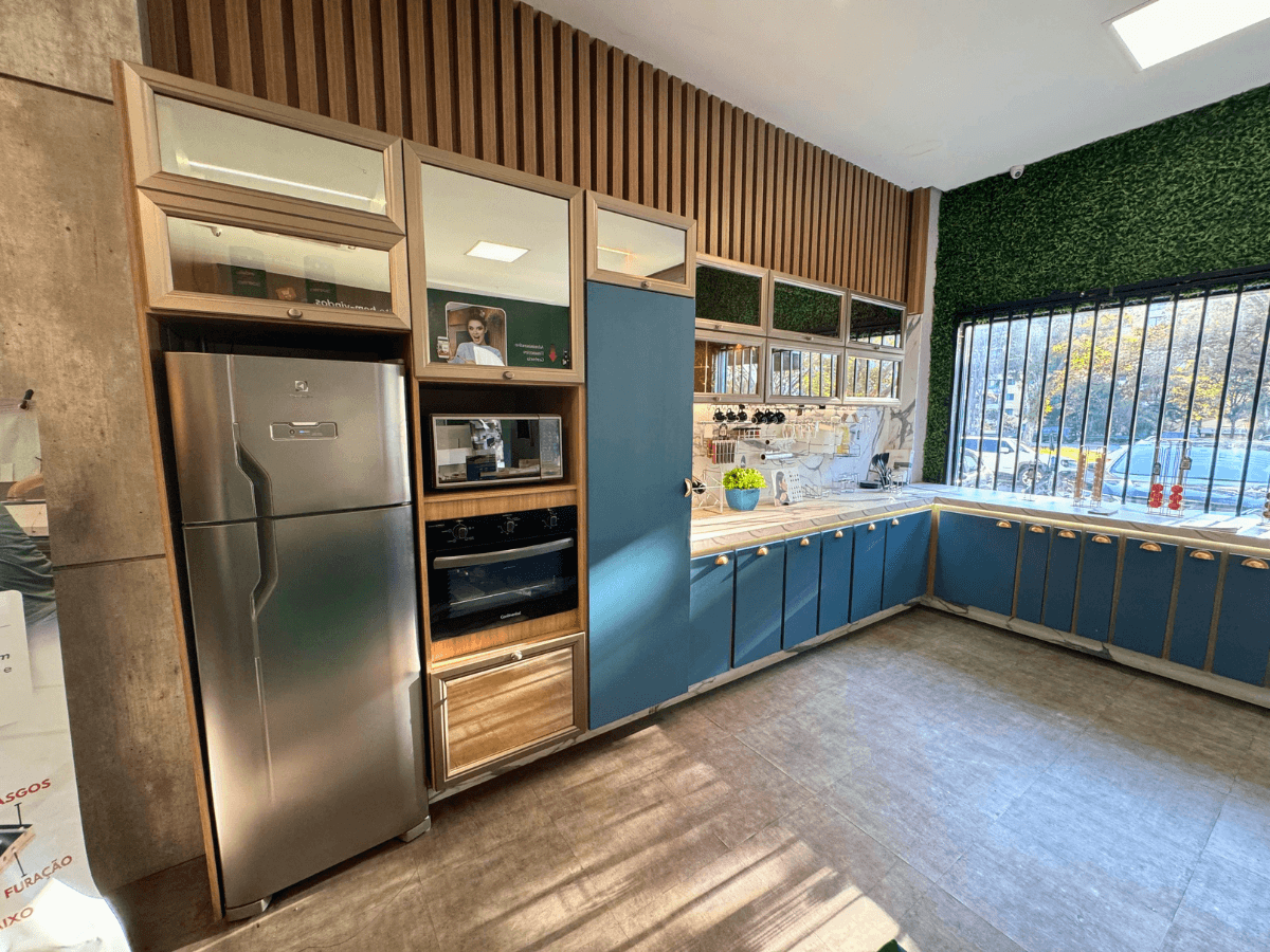 Cozinha montada no showroom, com armários, forno e geladeira embutidos.