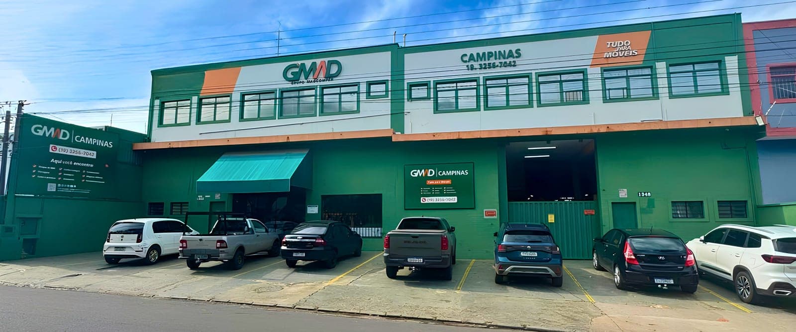 A fachada atual da GMAD Campinas, verde e laranja, com o estacionamento em frente.